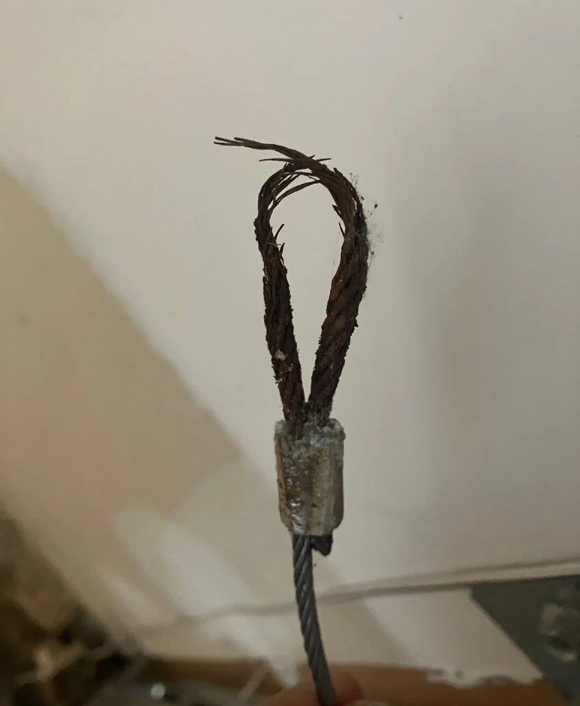 Close view of a garage door lift cable at the bottom bracket